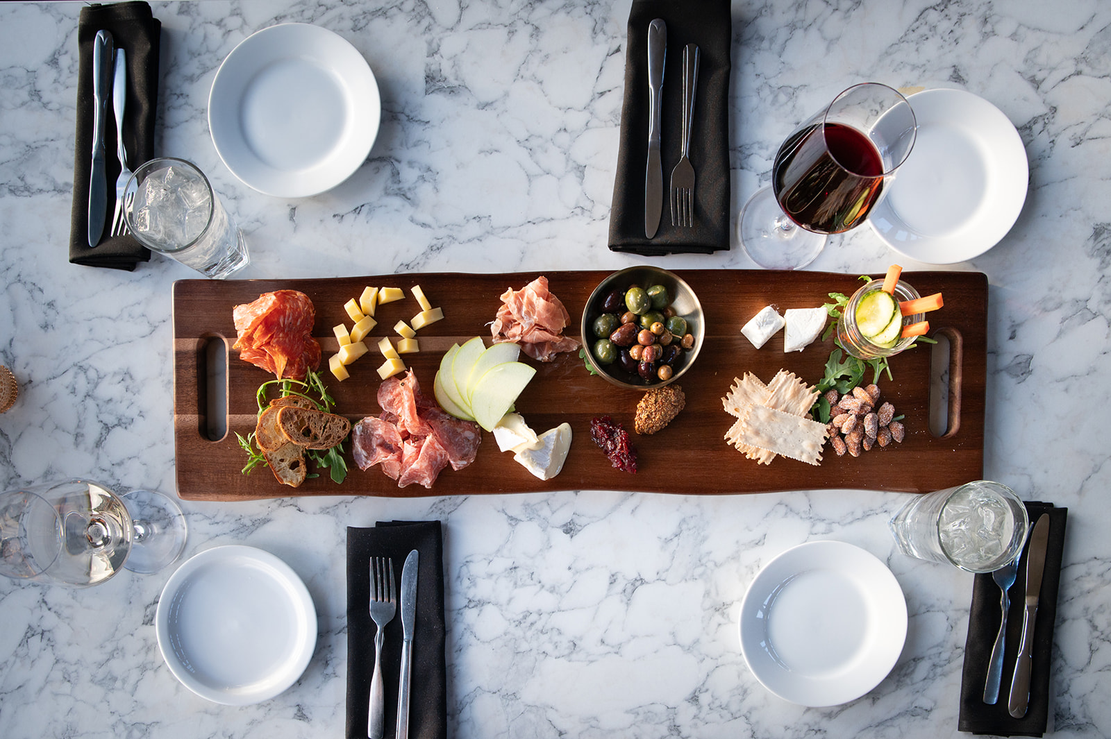 A wooden tray elegantly arranged with gourmet food showcasing Myril caterings exquisite offerings for a wine bar settingjpeg