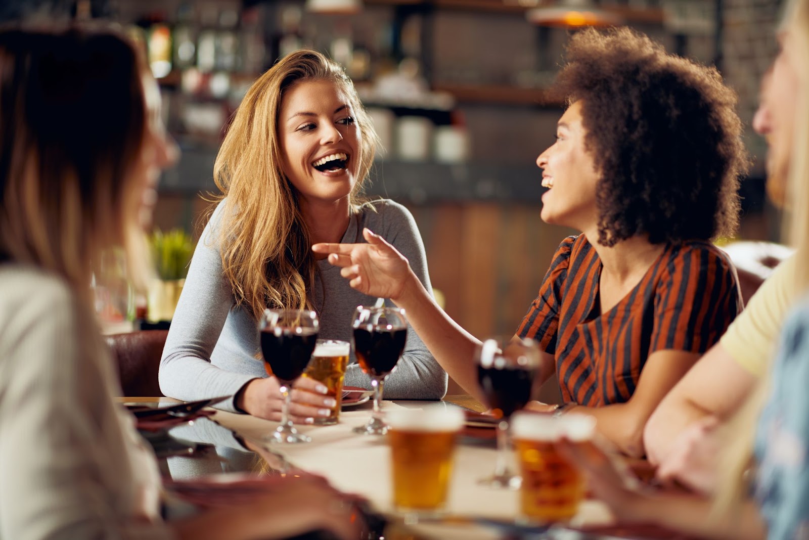 Three women joyfully laughing and enjoying wine together at a vibrant bar setting celebrating friendship and good timesjpeg