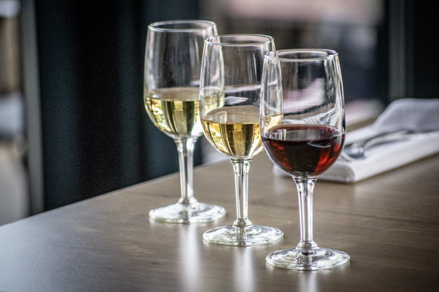 Three elegant glasses of wine arranged on a table, perfect for pairing with gourmet dishes at a wine bar.